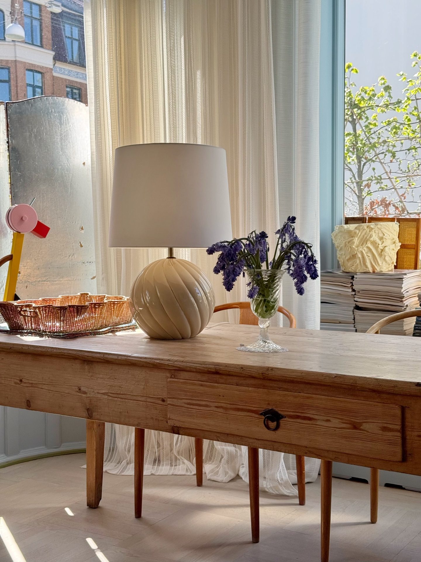 Round cream ceramic Tommaso Barbi style table lamp on a pine table in daylight