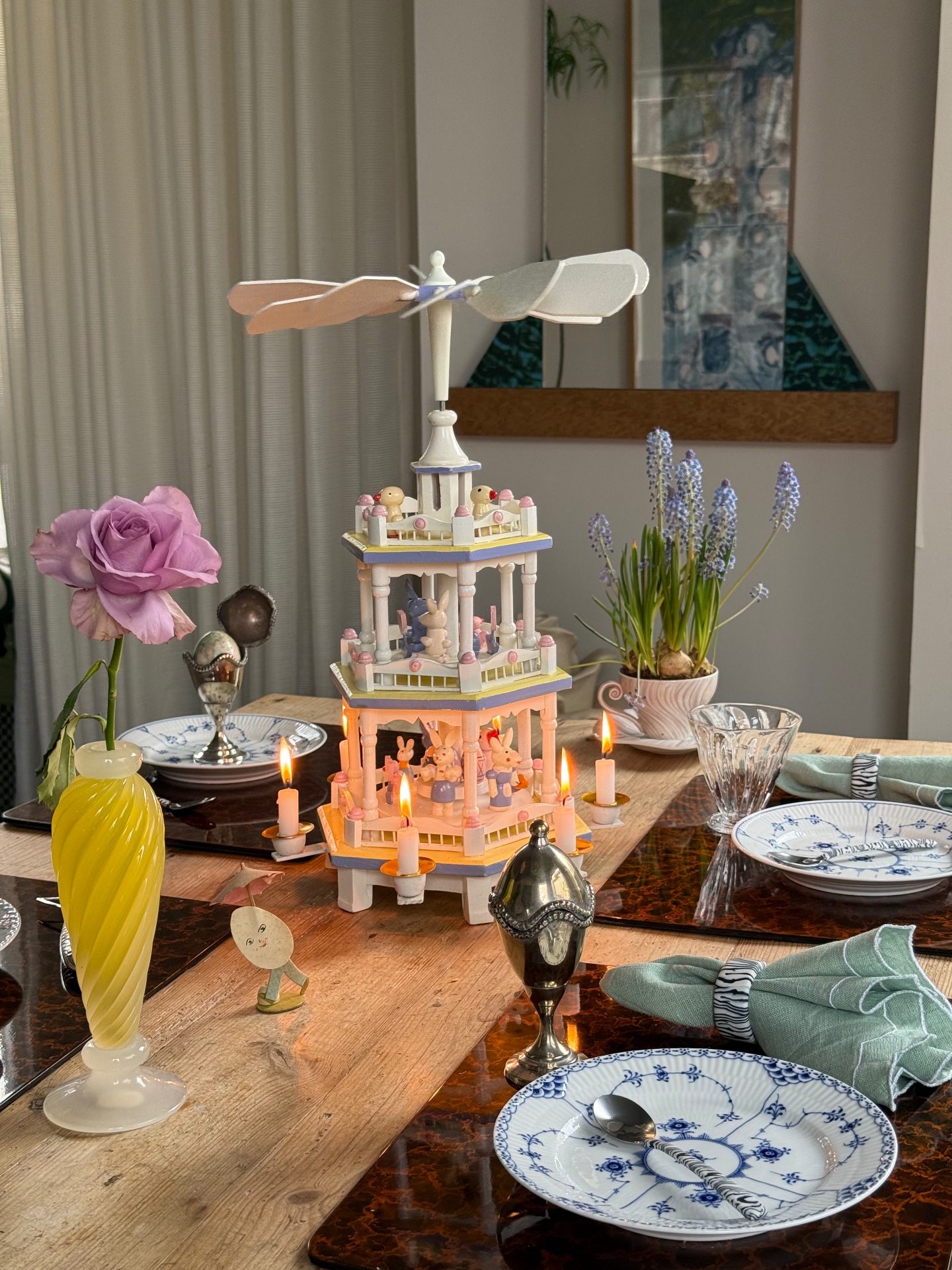 Vintage wooden Easter pyramid with lit candles on a set spring table with blue and white plates