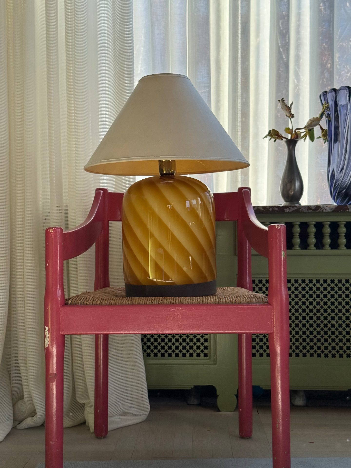 Amber glass vintage table lamp beside a chair in a calm interior