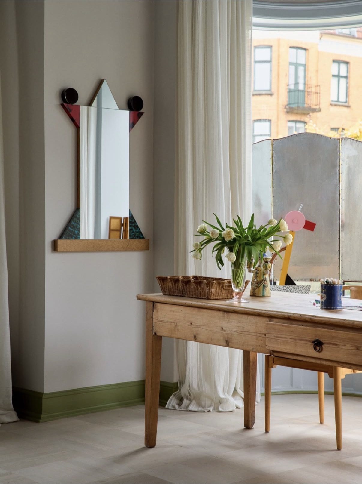 Pine console table with a vintage mirror, glass and flowers in a bright Copenhagen room
